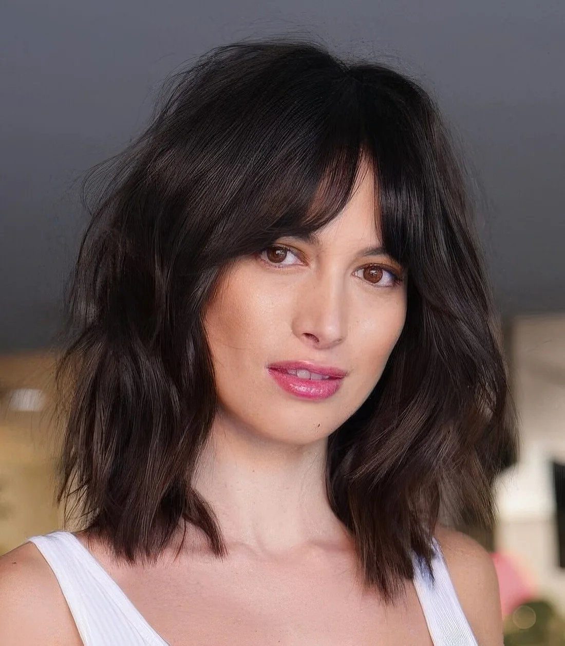 Black dimensional medium-length hairstyle with slight waves and bottleneck bangs.