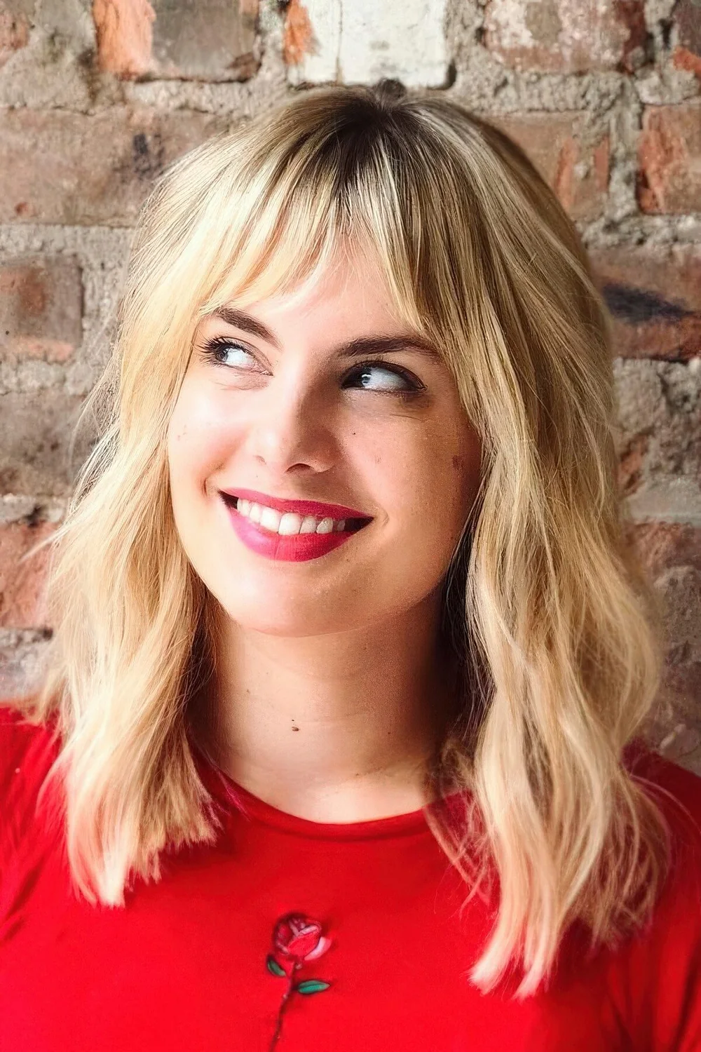 Blonde medium-length haircut with bottleneck bangs and messy waves.