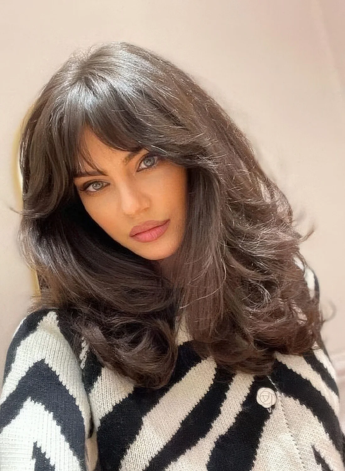 Dark brunette medium butterfly haircut on thick hair, with bottlneck bangs and waves.