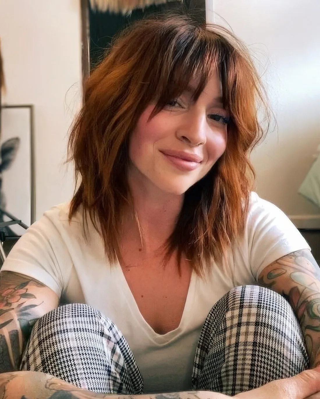 Shaggy medium-length copper haircut with messy waves and bottleneck bangs.