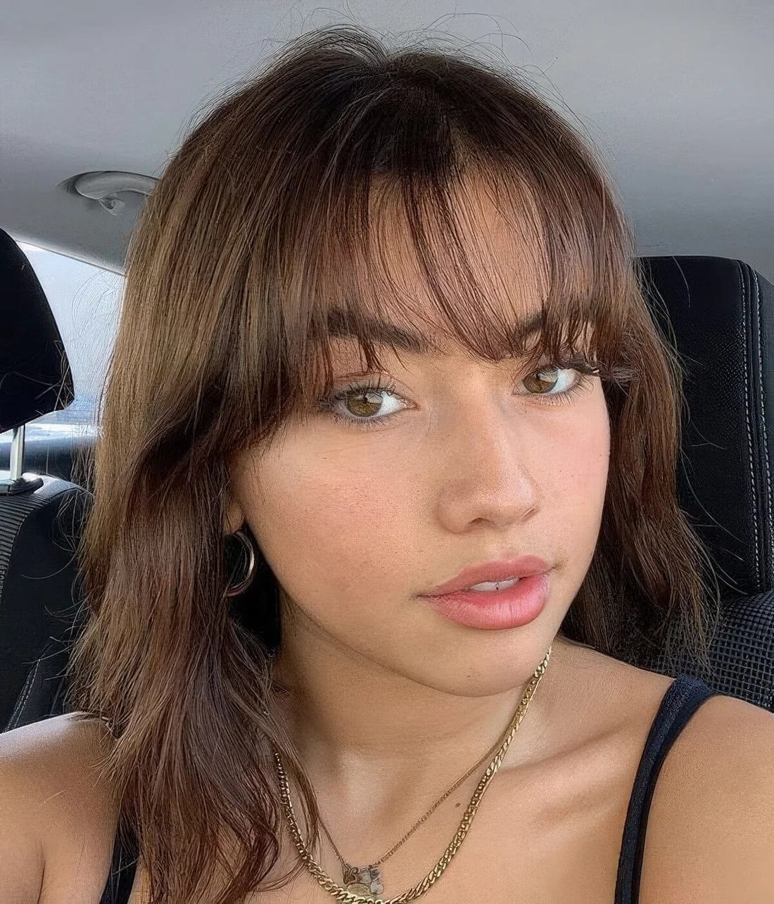 Dark brunette wavy medium-length hairstyle with wispy bangs.