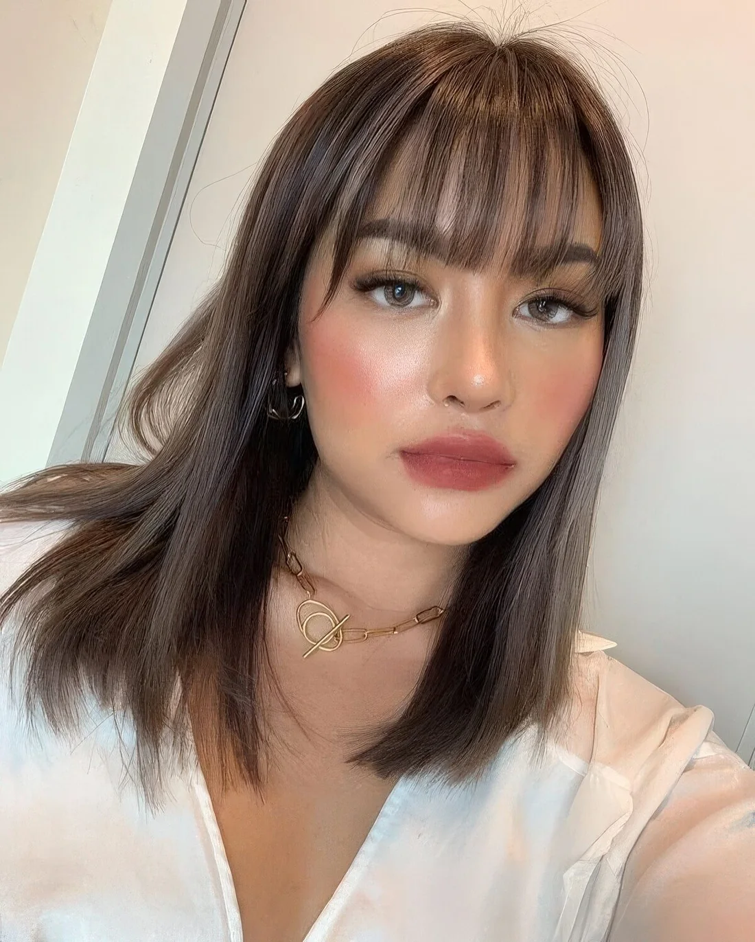 Medium-length brunette straight hair with wispy bangs to accent the eyes at their best.