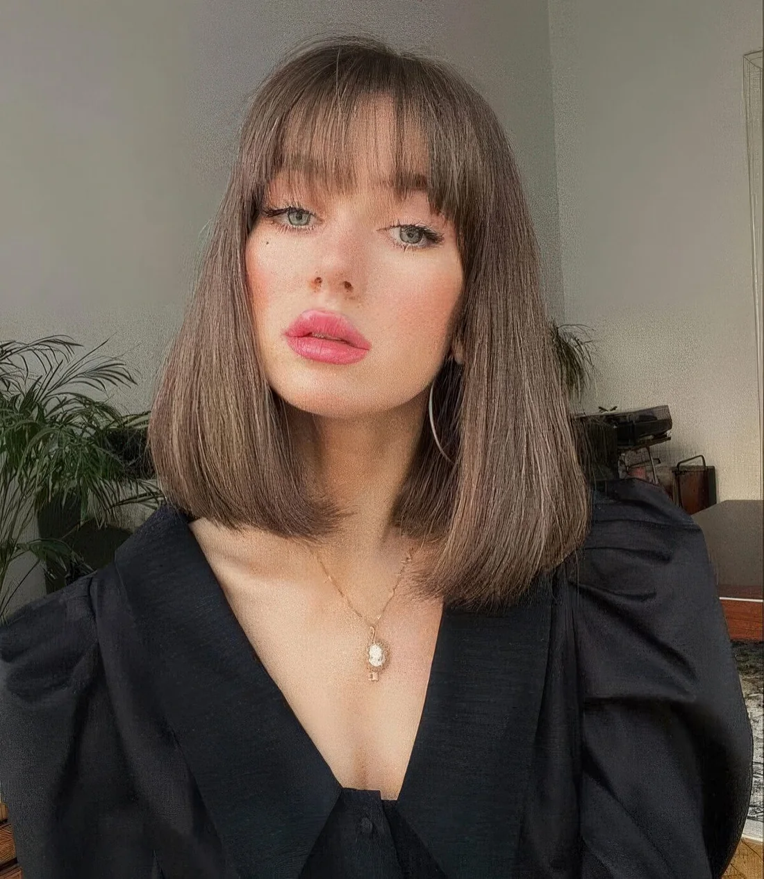 Medium-length brunette hair with wispy bangs and rounded ends.