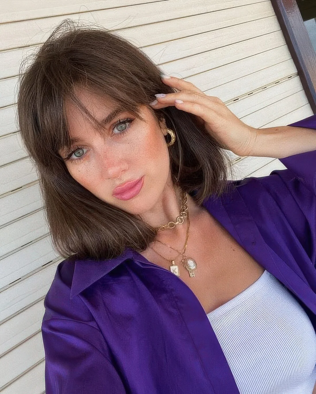Medium-length brunette hair with wispy bangs.