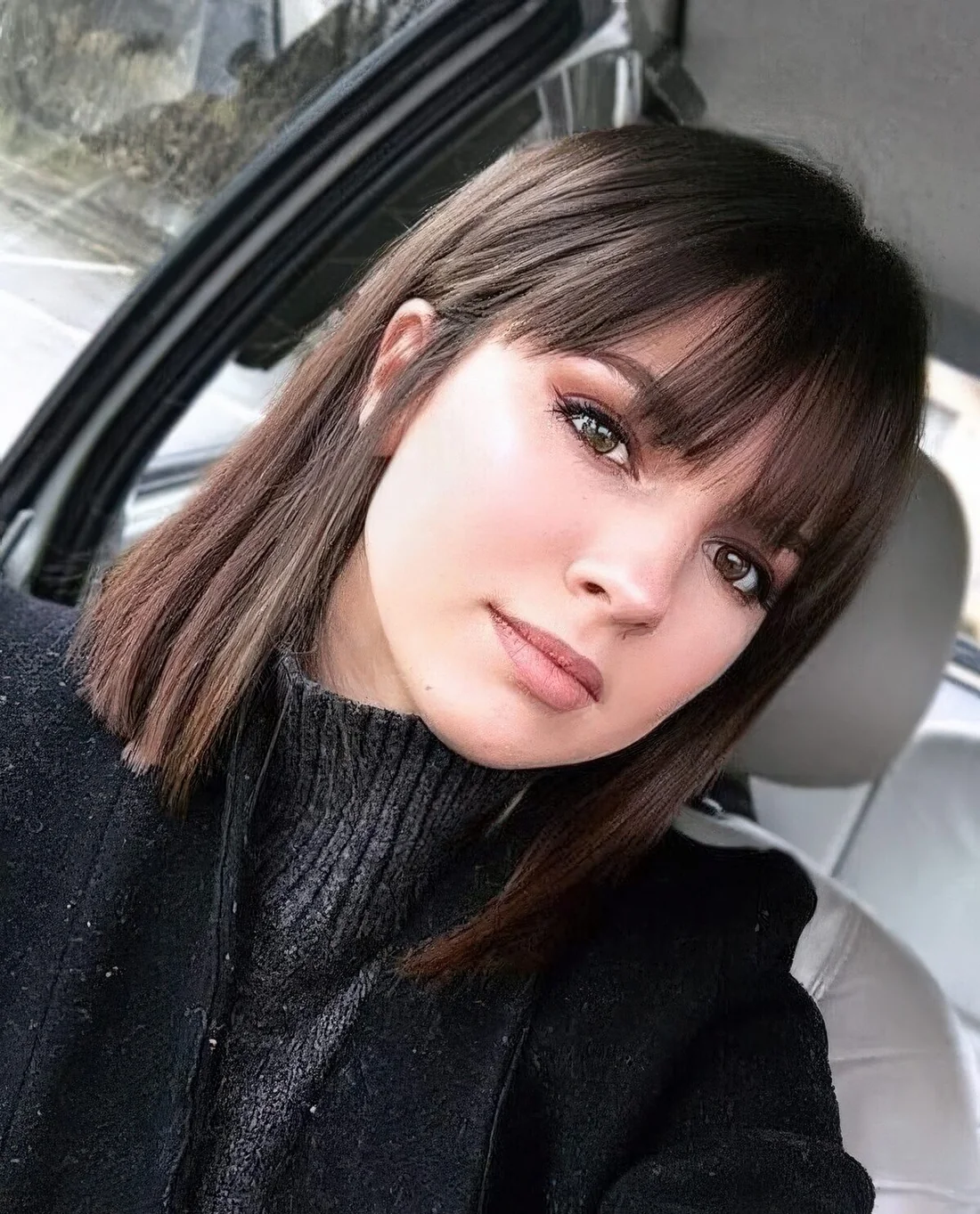 Medium-length dark brown hair with wispy bangs.