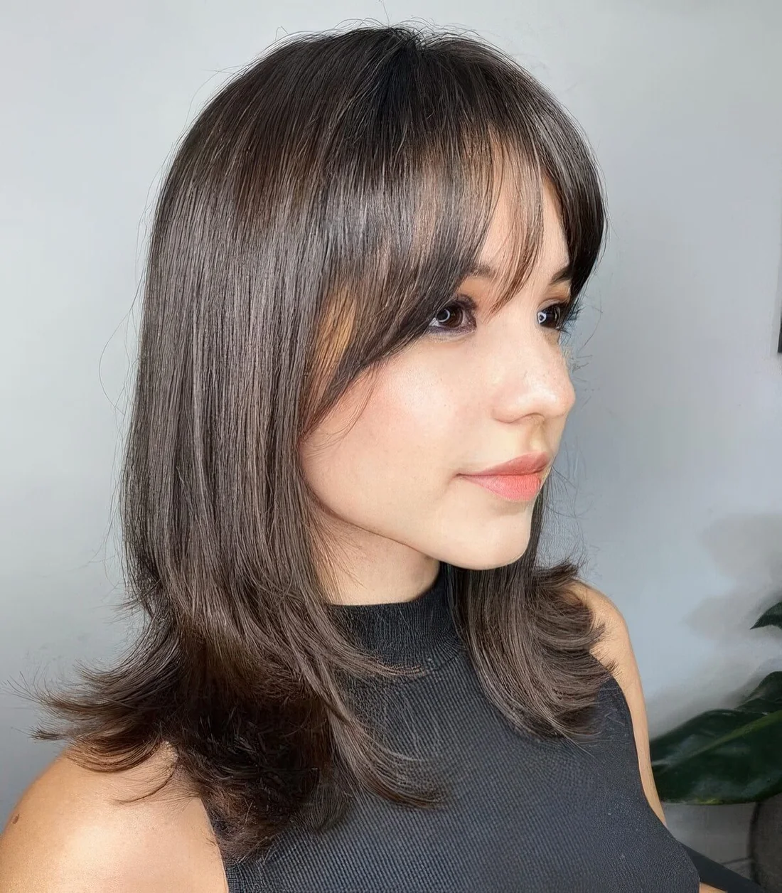 Medium-length dark brown hair with a bit of layers and wispy bangs.