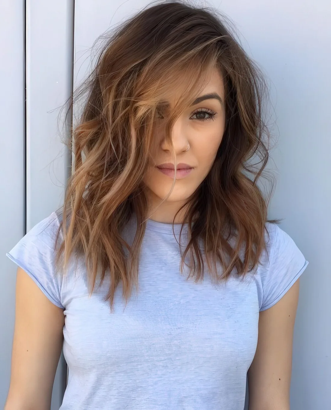 Medium haircut with layers, bangs and blonde balayage for a chic look.
