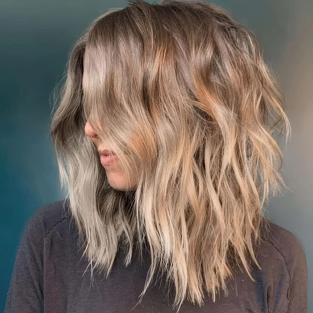 Beach bronde shaggy haircut with beach waves and center part.