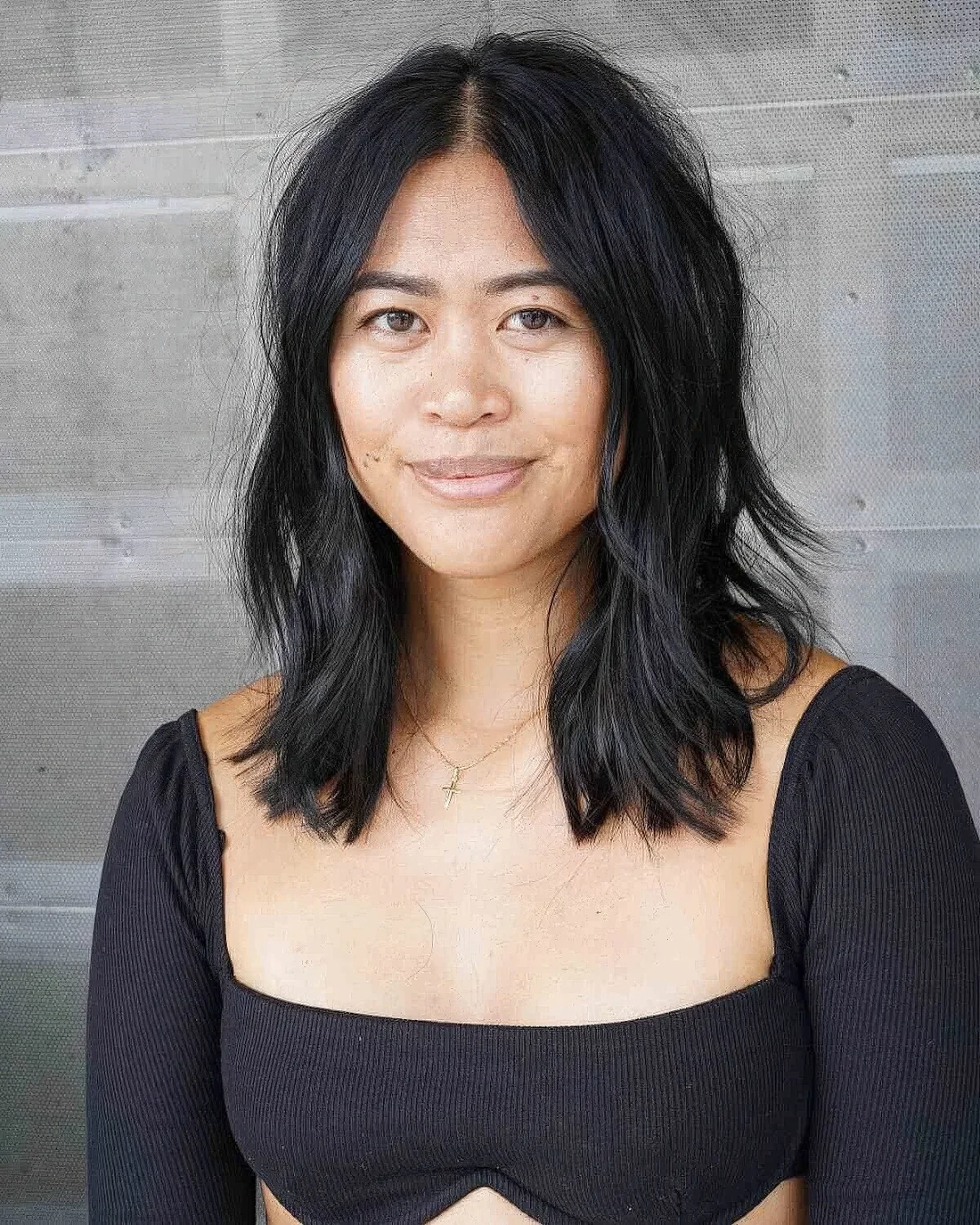 Black shaggy choppy haircut with center part, heavily textured layers and face-framing ones for a rock n roll vibe.