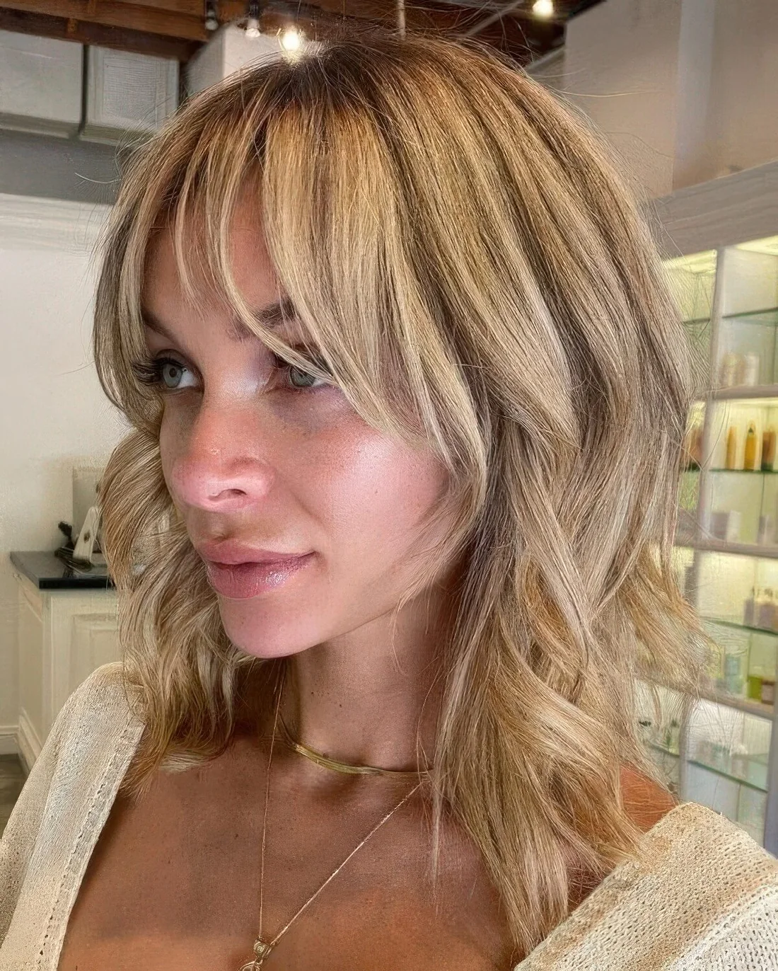 Blonde medium-length choppy layered haircut with side and wispy bangs paired.