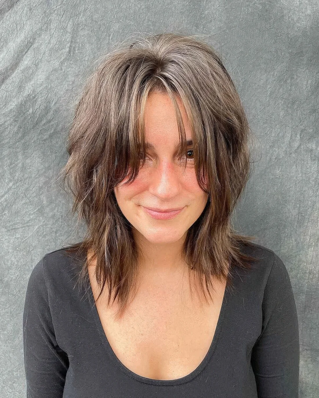 Brown shoulder-length choppy haircut that resembles a wolf cut.