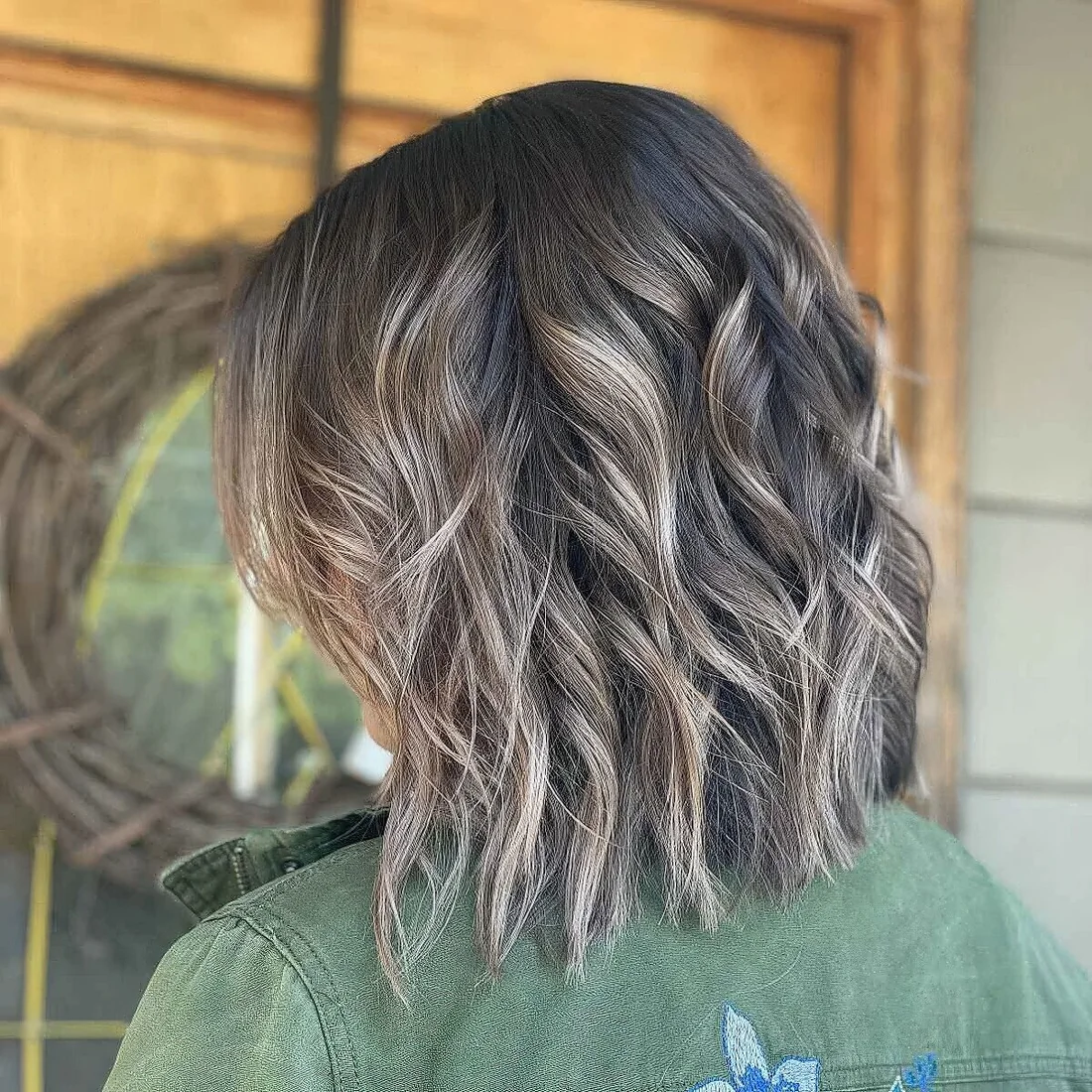 Dark brown medium haircut with bronde highlights and waves plus choppy layers.