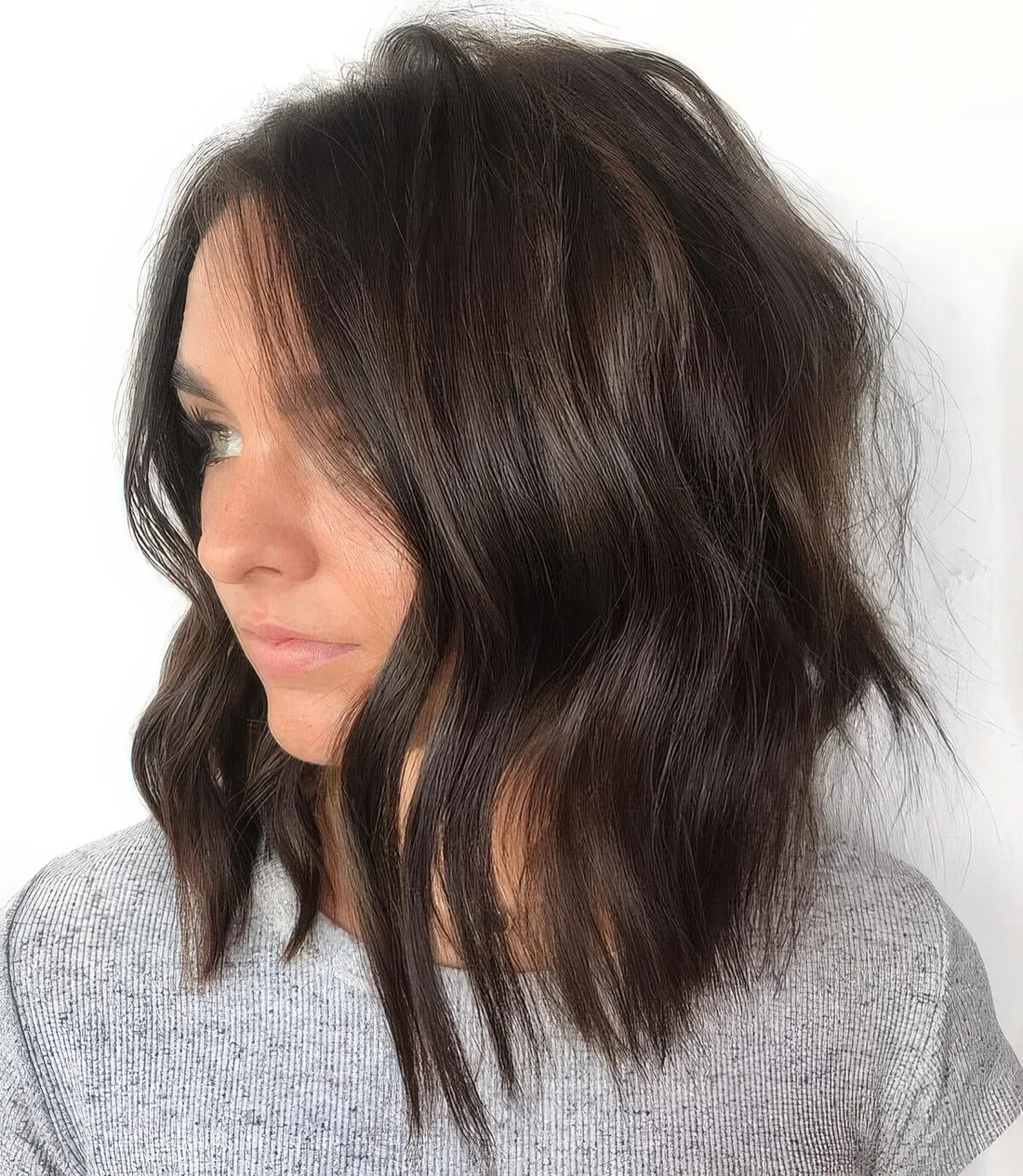 Dark brown wavy shaggy and choppy haircut with side part.
