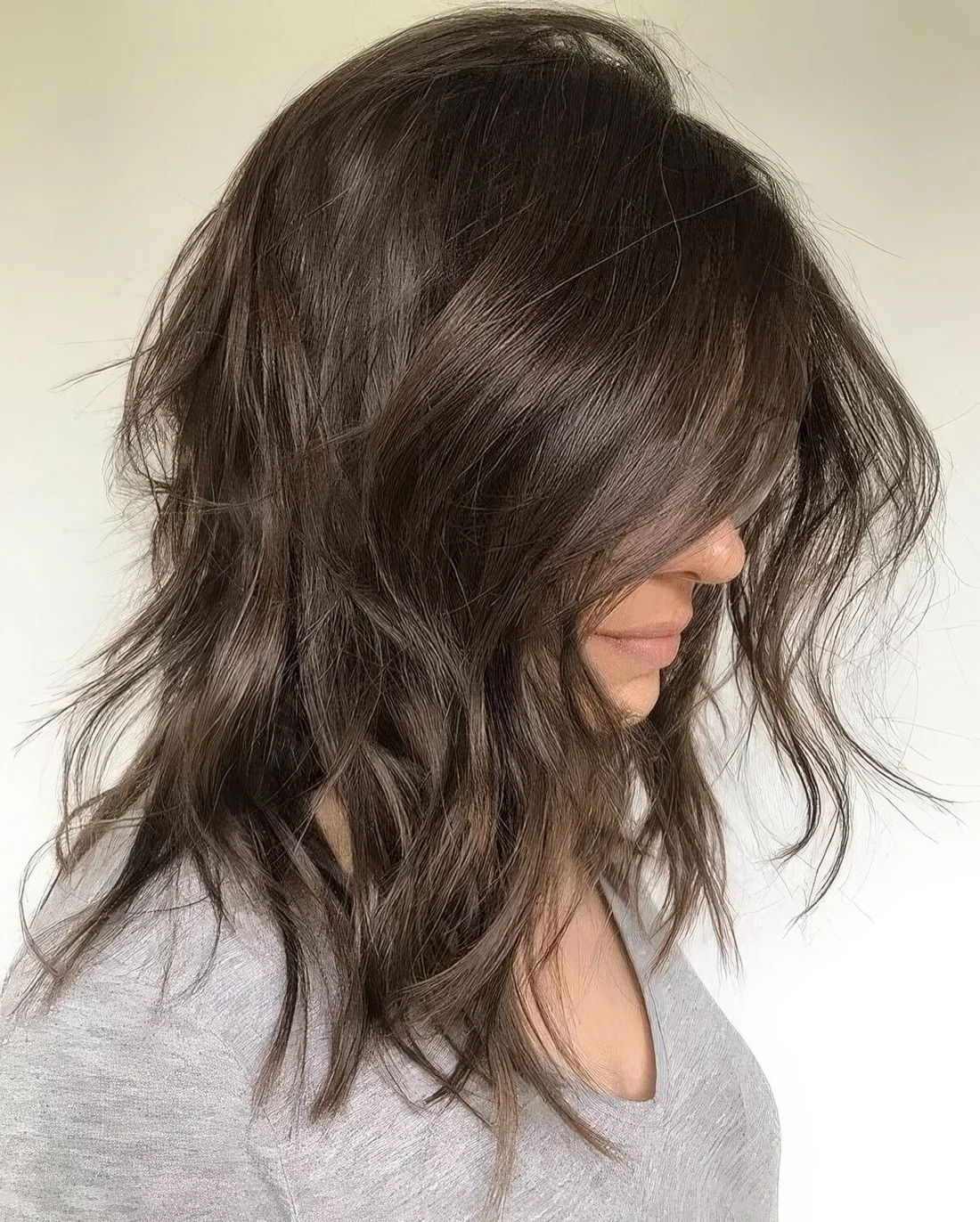Messy dark brown medium-length choppy haircut with shaggy layers and a bit of wavy ends.