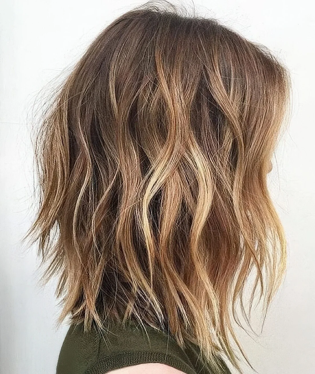 Shaggy and choppy brown hair with blonde balayage and beach waves.