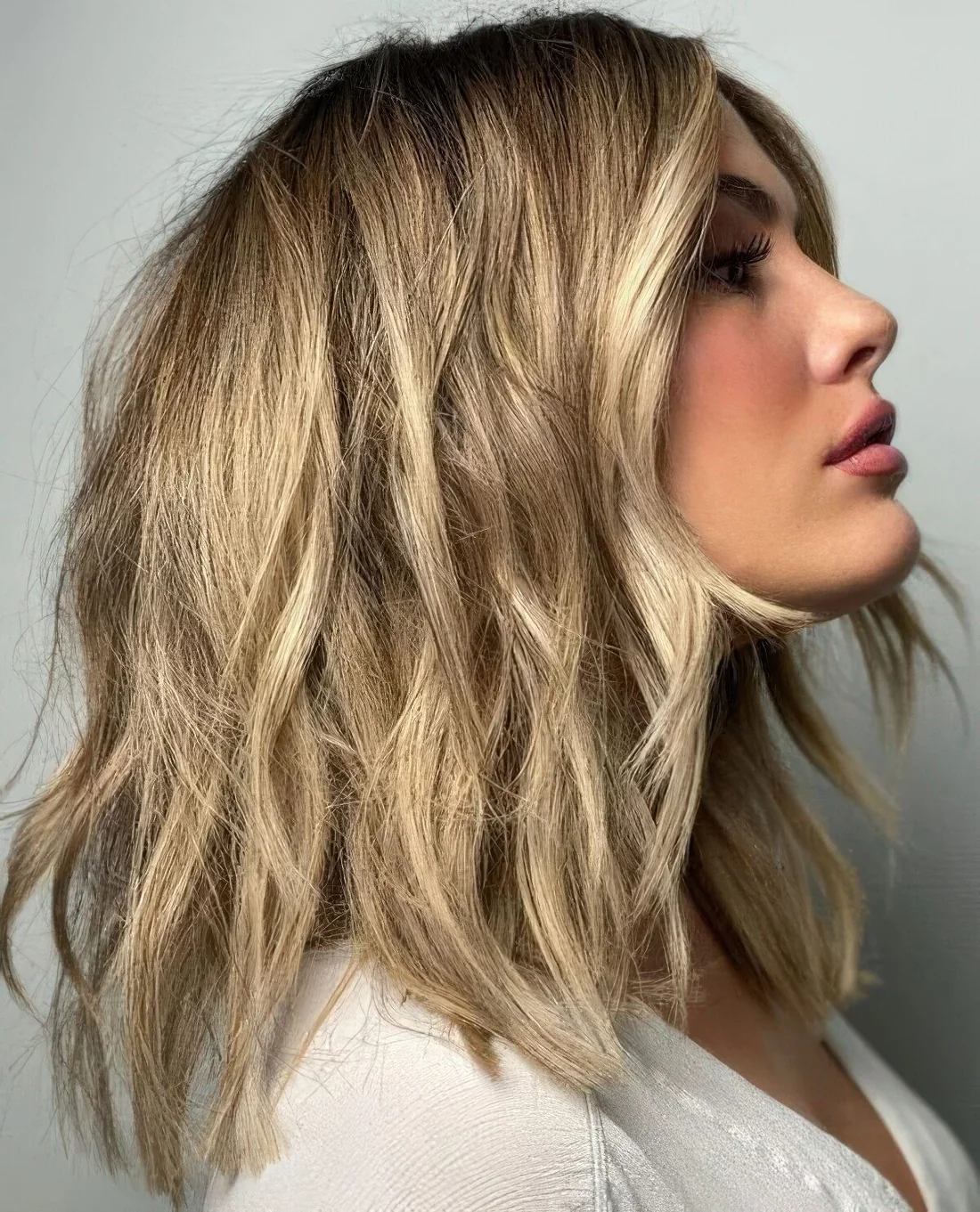 Golden blonde choppy and layered hair with a darker root and a bit of texture.