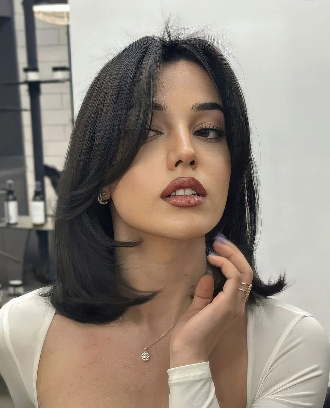 Black medium-length hairstyle with curtain bangs, curled ends and a bit of volume.