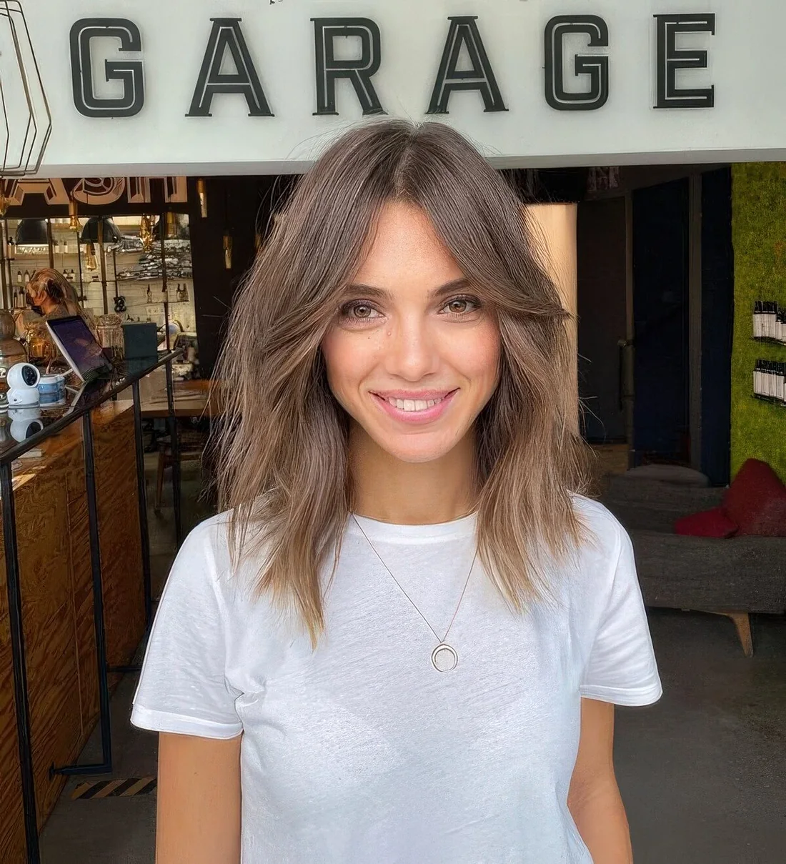 Light brunette shoulder-length hairstyle with curtain bangs and messy texture.