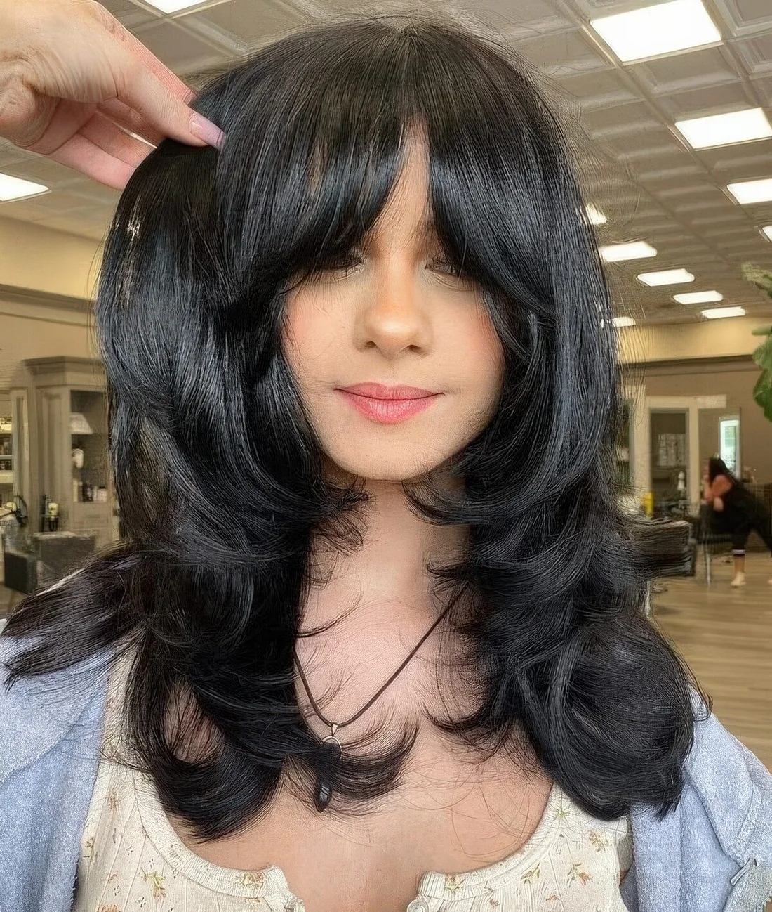 Medium black butterfly haircut with curtain bangs and curled ends and a shiny touch.