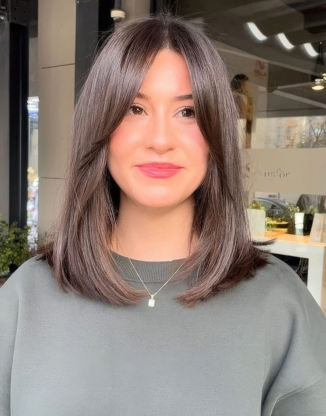 Medium-length dark brown haircut with curtain bangs and a perfect touch of shine.