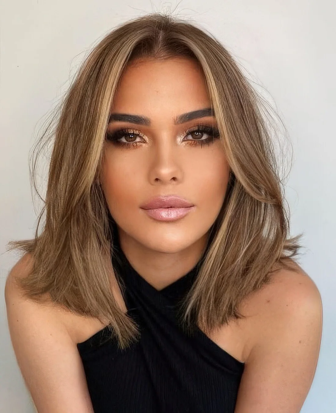 Soft brown outgrown bob with a bit of blonde highlights and soft curtain bangs dyed blonde, too.