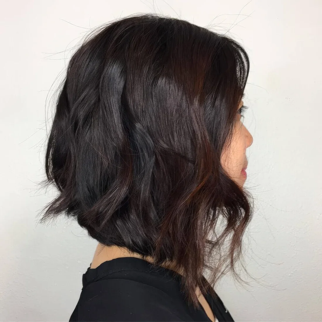 Black razor cut lob with an angle and burgundy highlights.