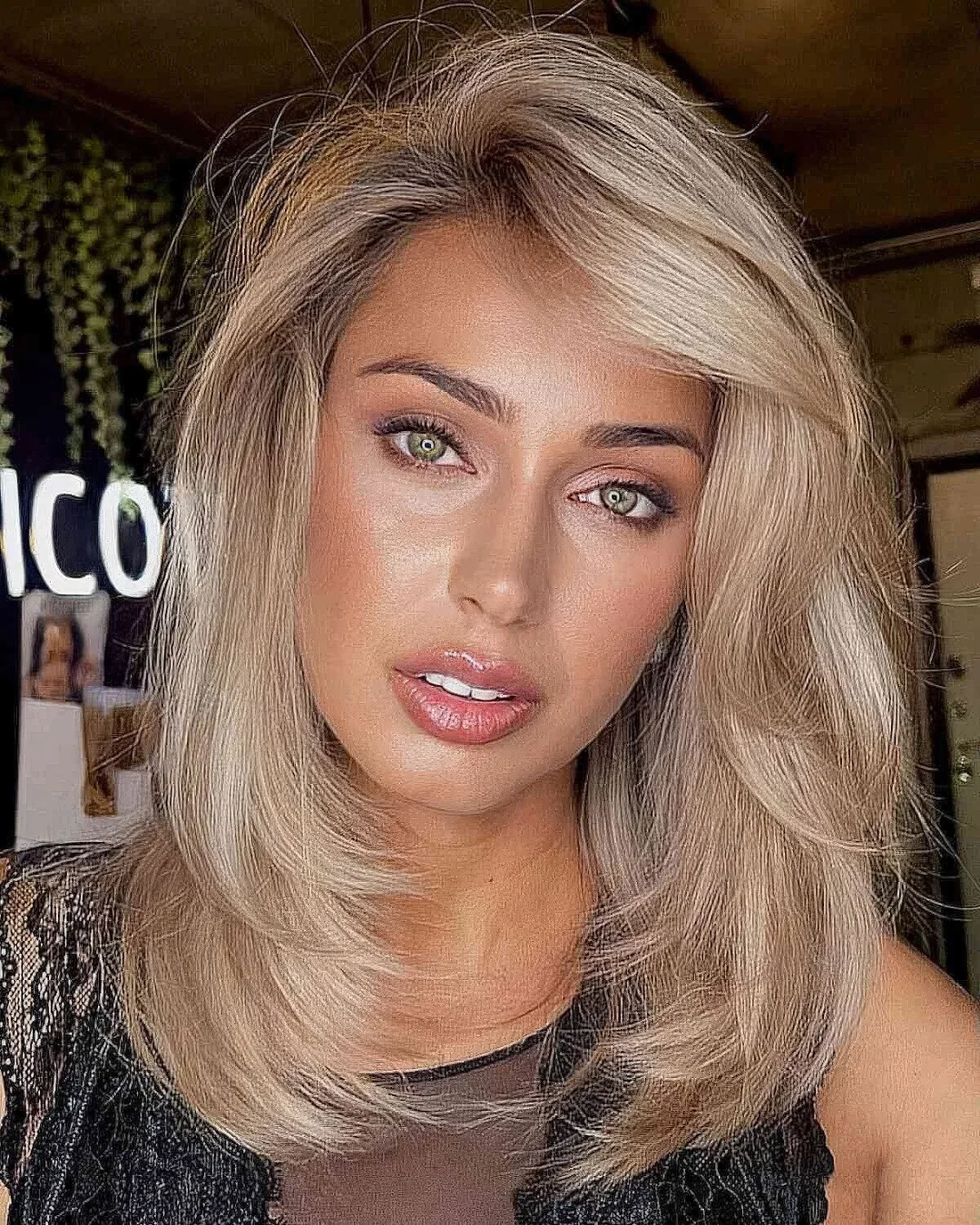 Medium blonde layered haircut with a swoop bang.