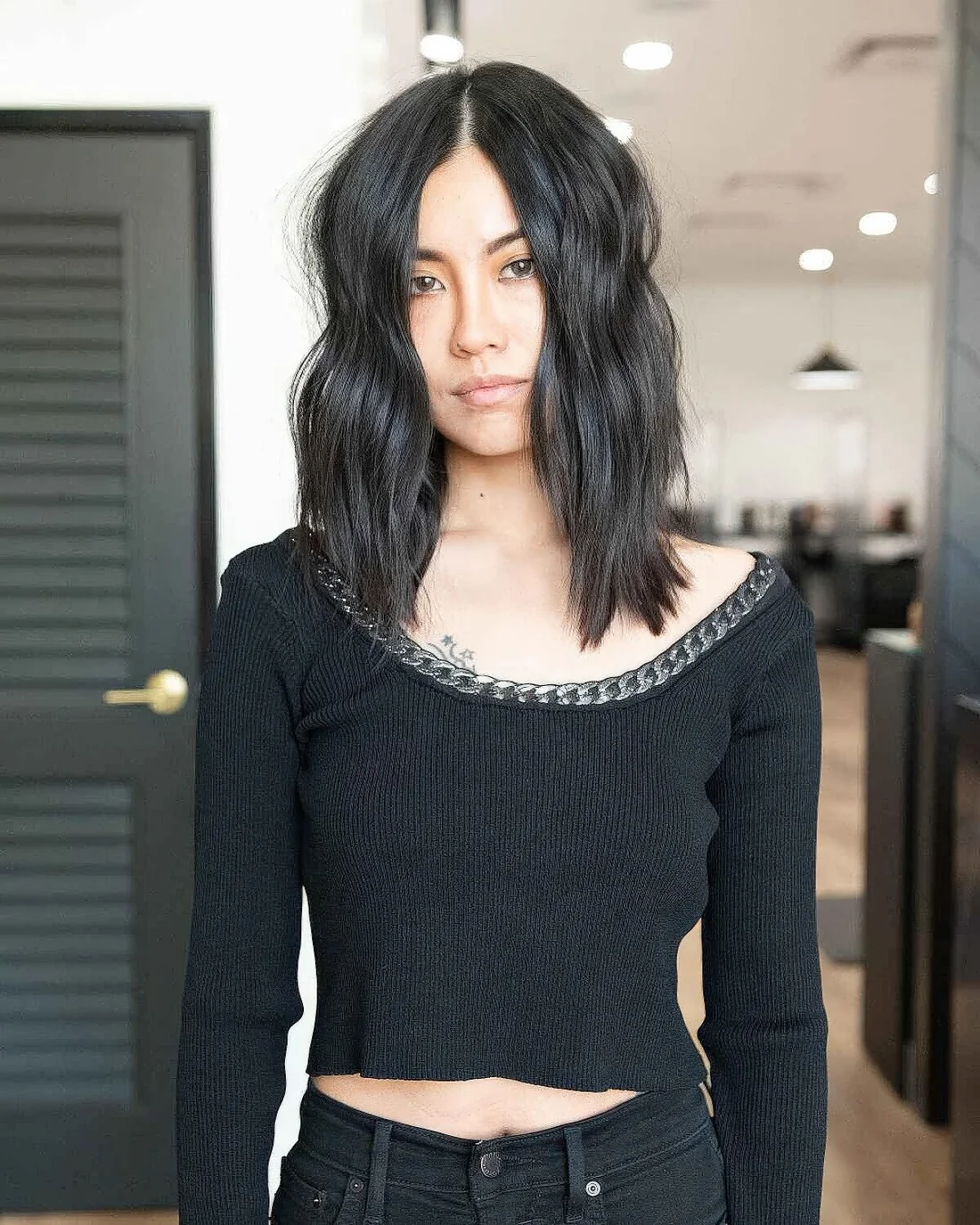 Black mid length layered hair with center part and waves.