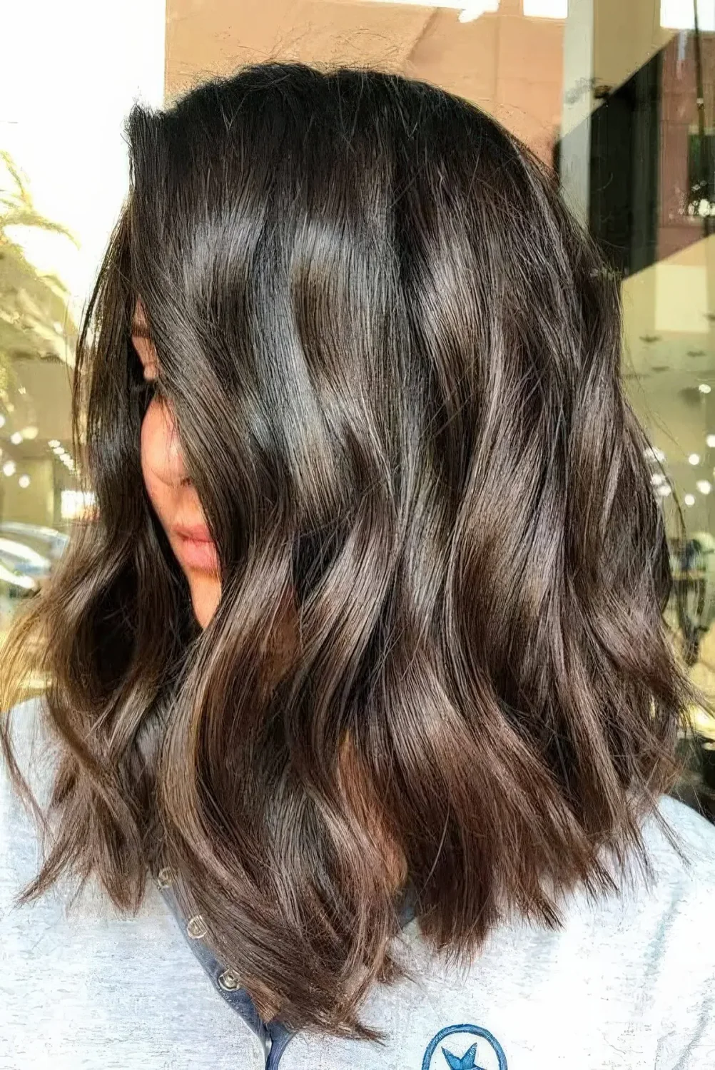 Dark brunette medium-length wavy haircut with highlights.