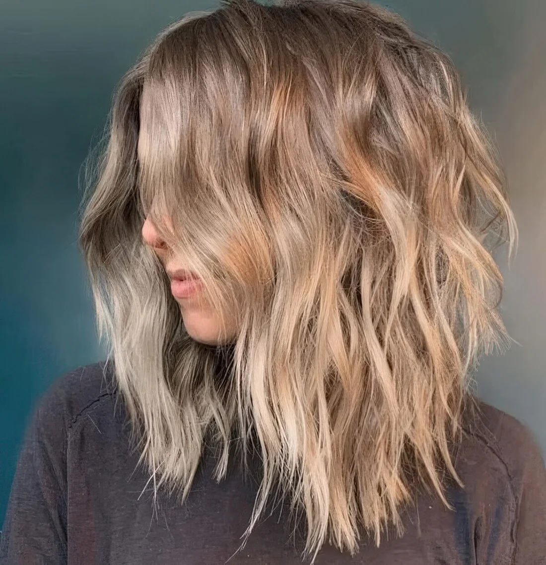 Beach bronde shaggy haircut with beach waves and center part.