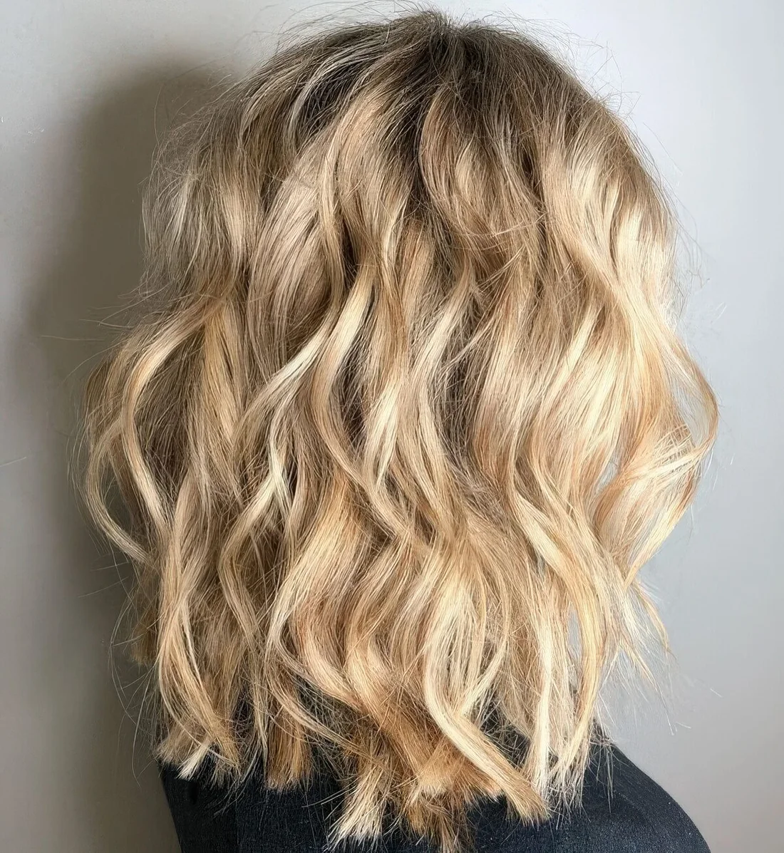 Blonde medium-length wavy haircut with messy beach waves.