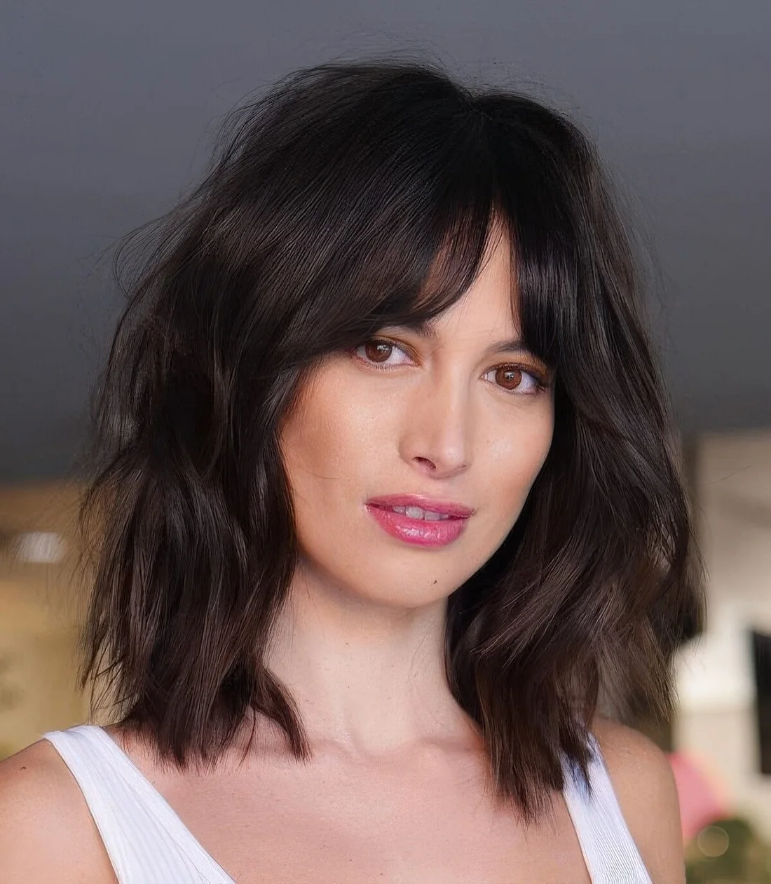 Black dimensional medium-length hairstyle with slight waves and bottleneck bangs.