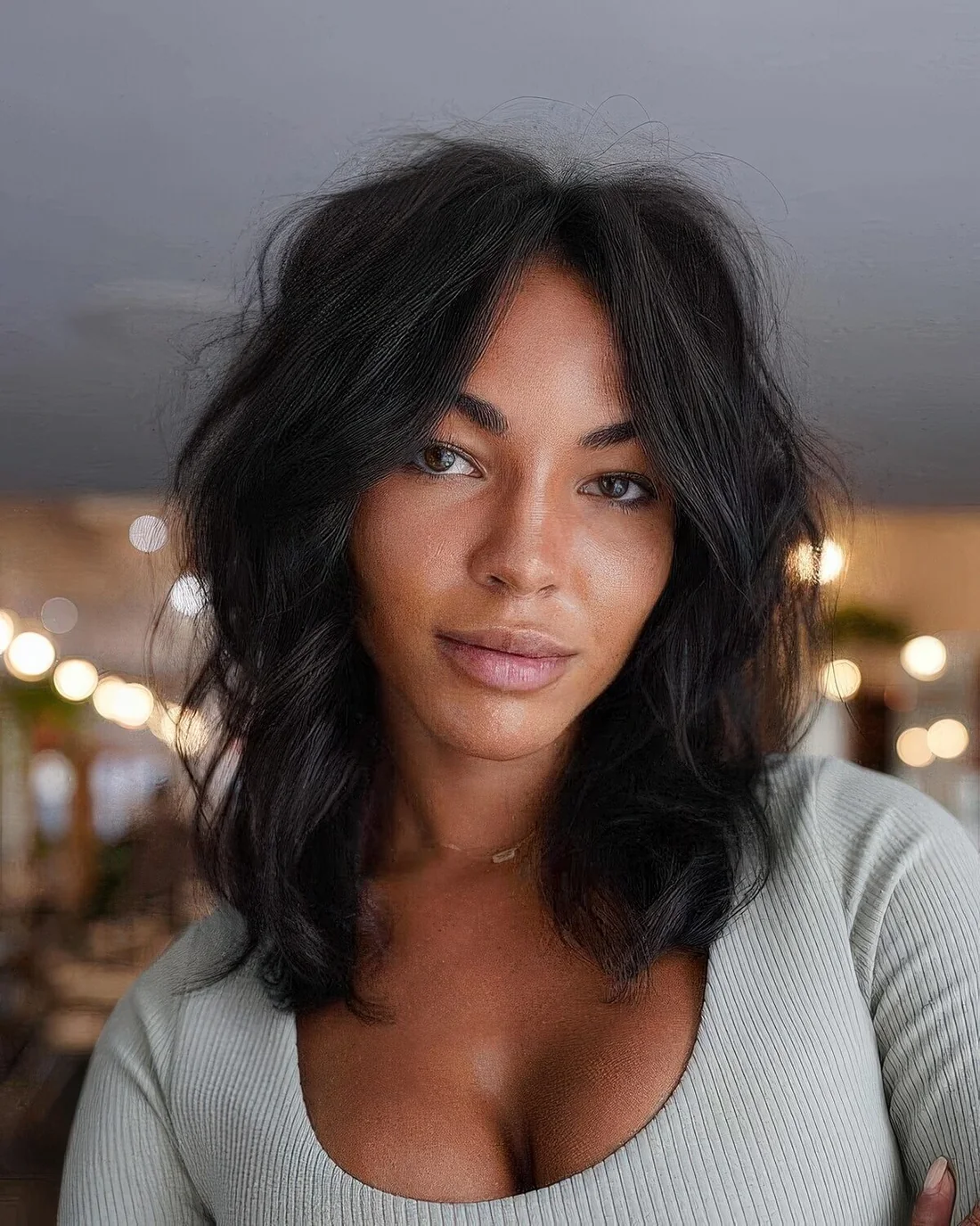 Black medium-length wavy haircut with waves and a lot of volume.