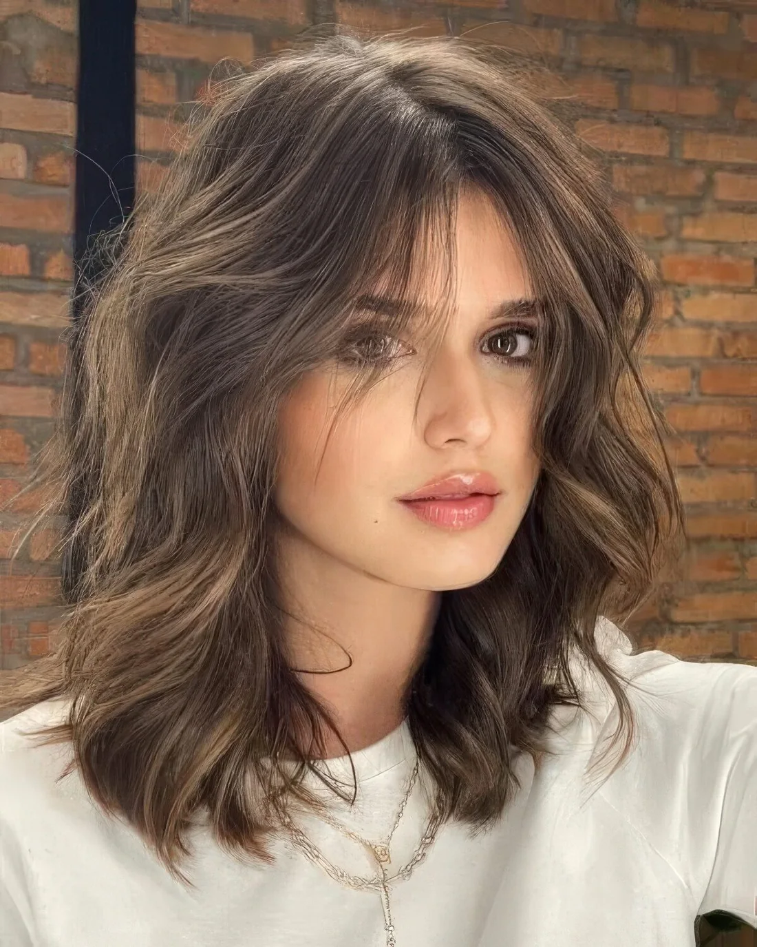 Brown medium-length wavy hairstyle with face-framing layers.