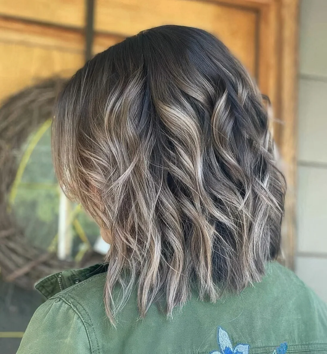 Dark brown medium haircut with bronde highlights and waves plus choppy layers.