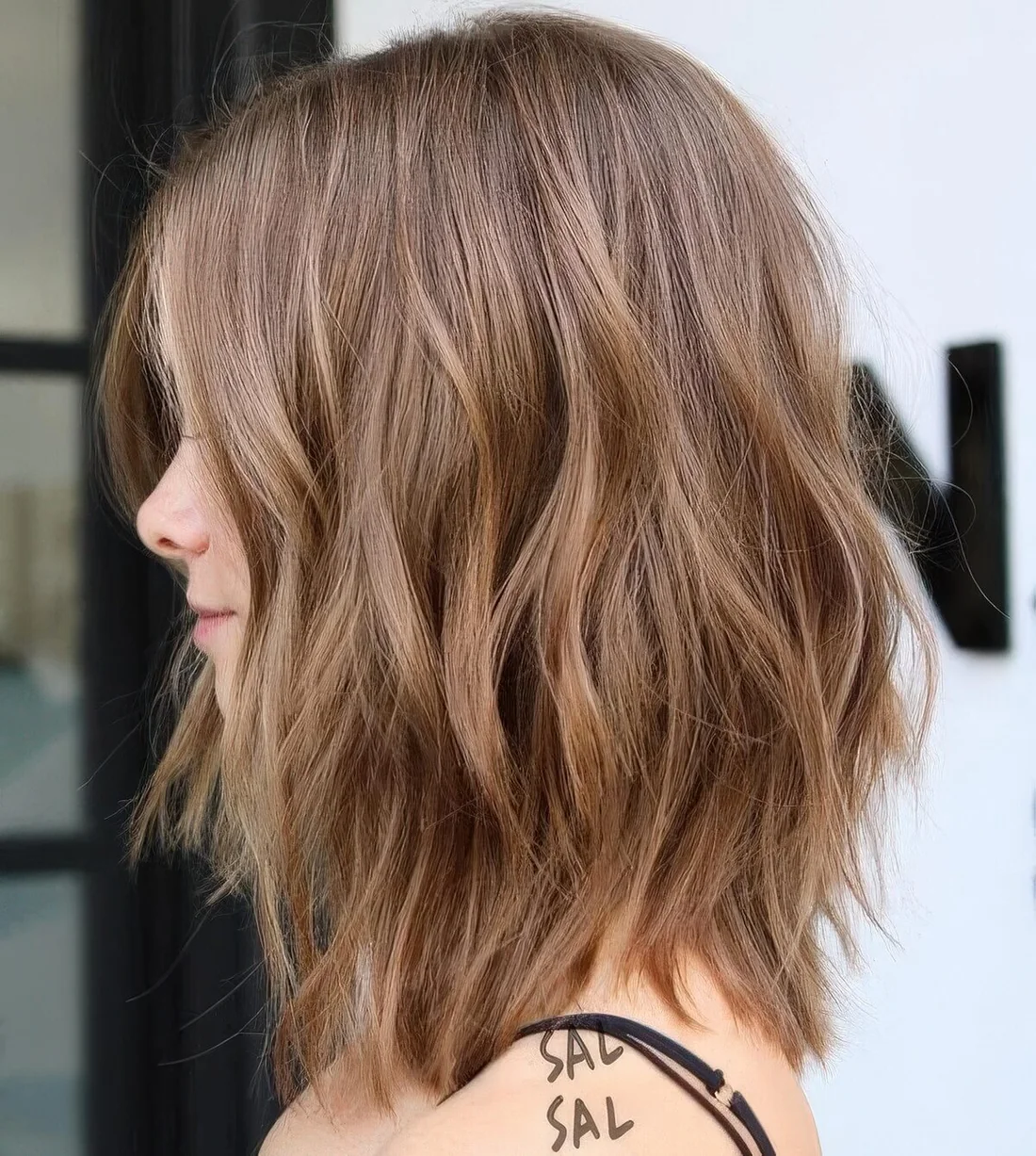 Soft brown choppy long bob with subtle highlights and waves and face-framing layers.