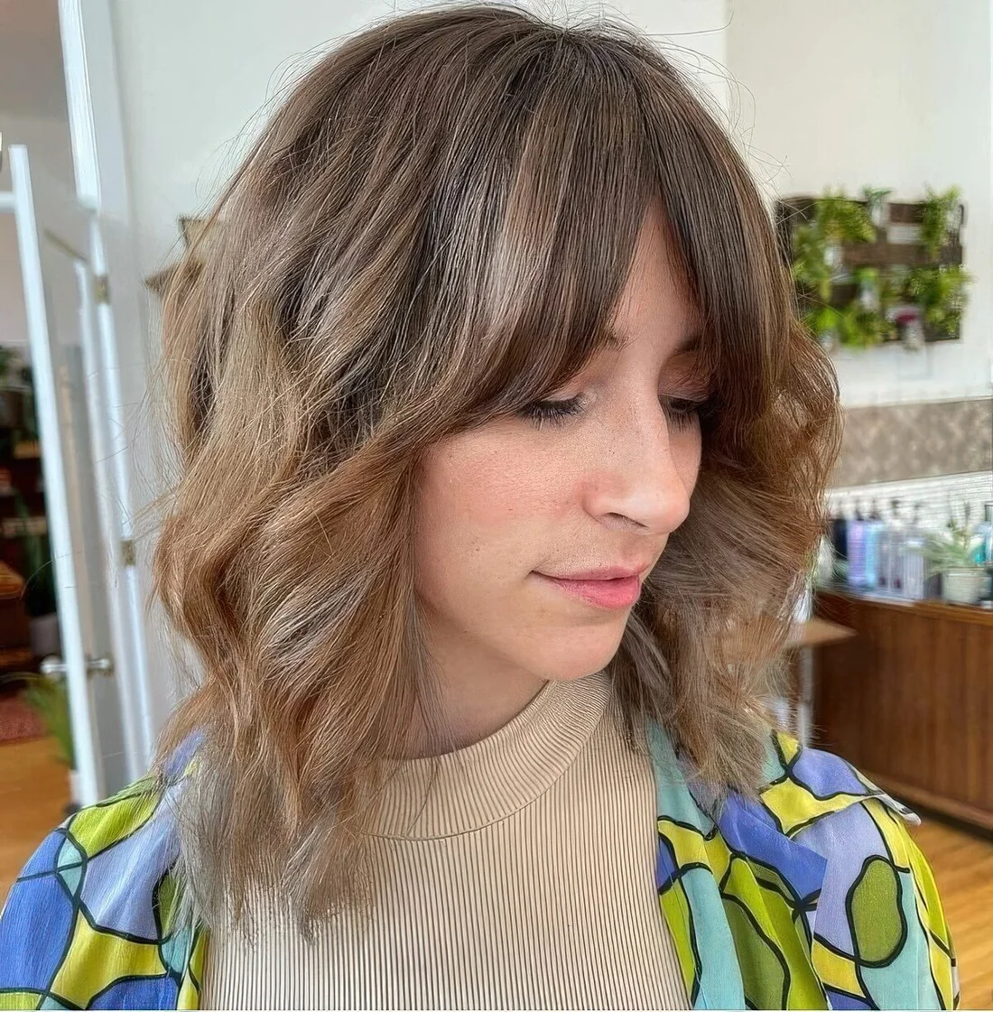 Light brown long wavy bob with curtain fringe and highlights.