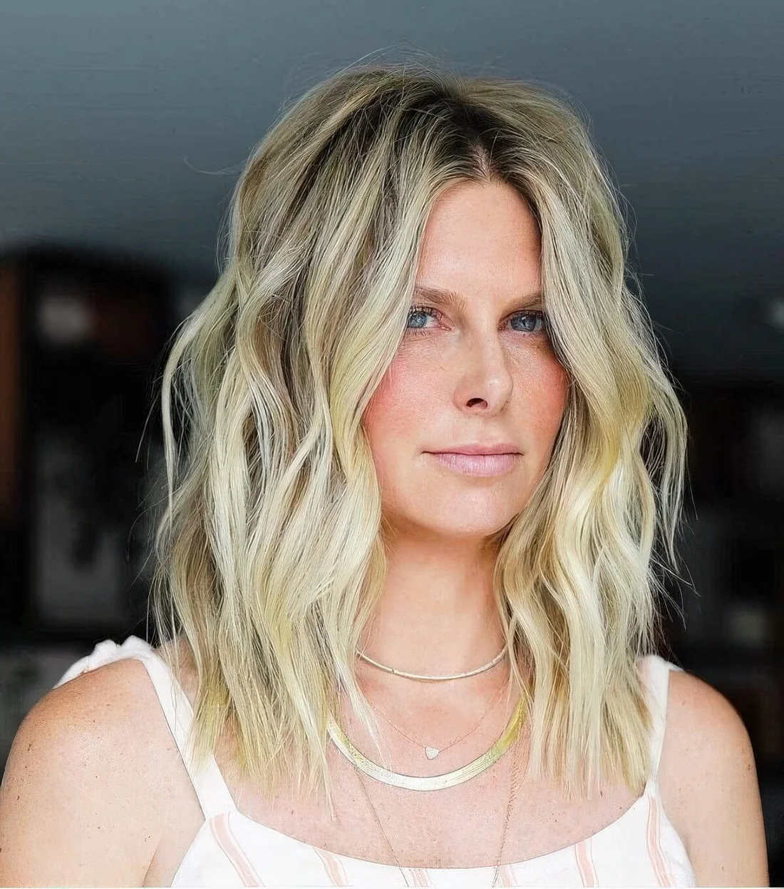 Medium layered and choppy haircut in blonde, with darker root and layers.
