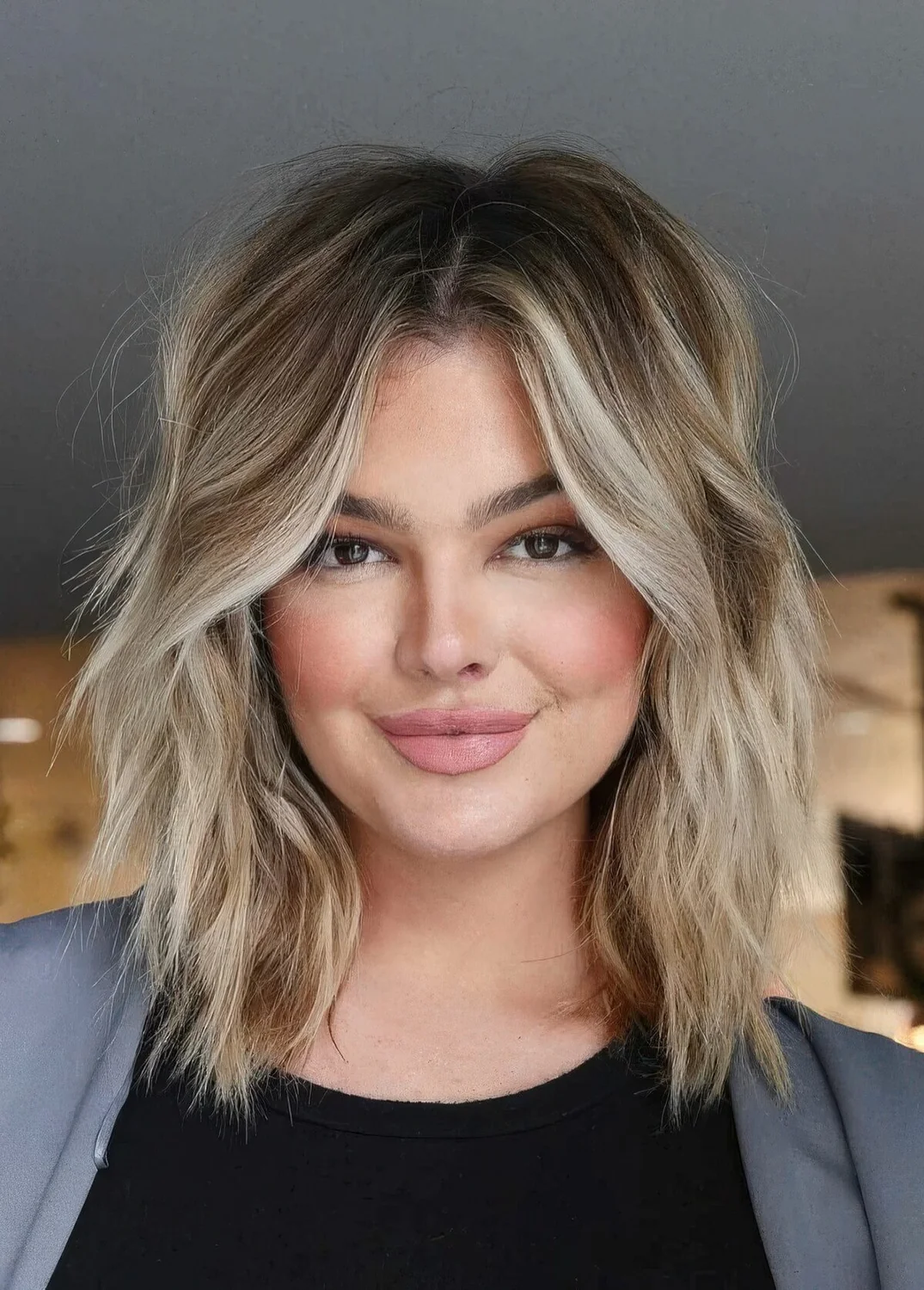 Medium layered and choppy haircut with blonde balayage and waves.