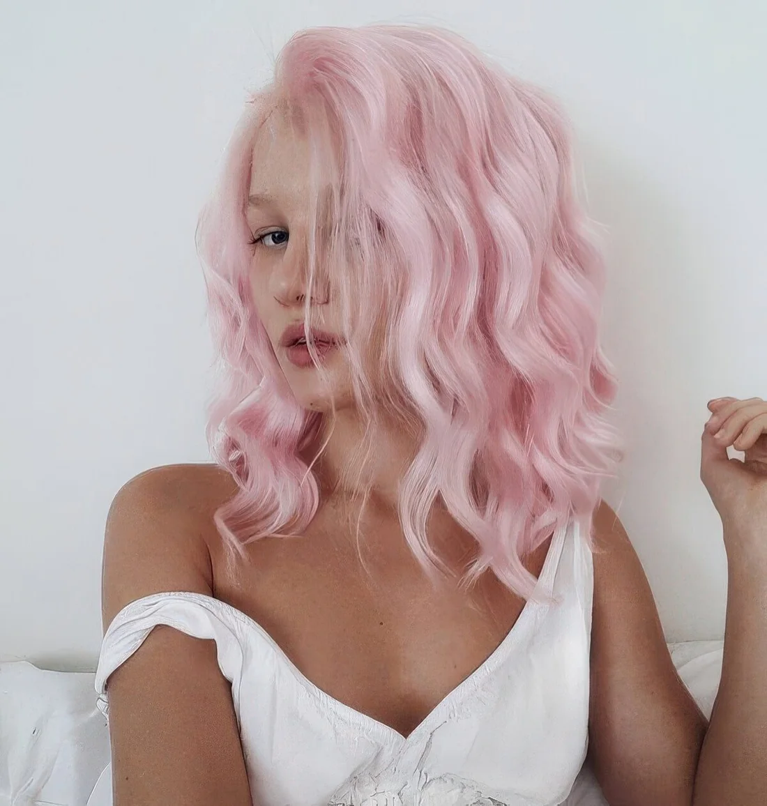 Shoulder-length bubblegum pink wavy hairstyle with much volume.