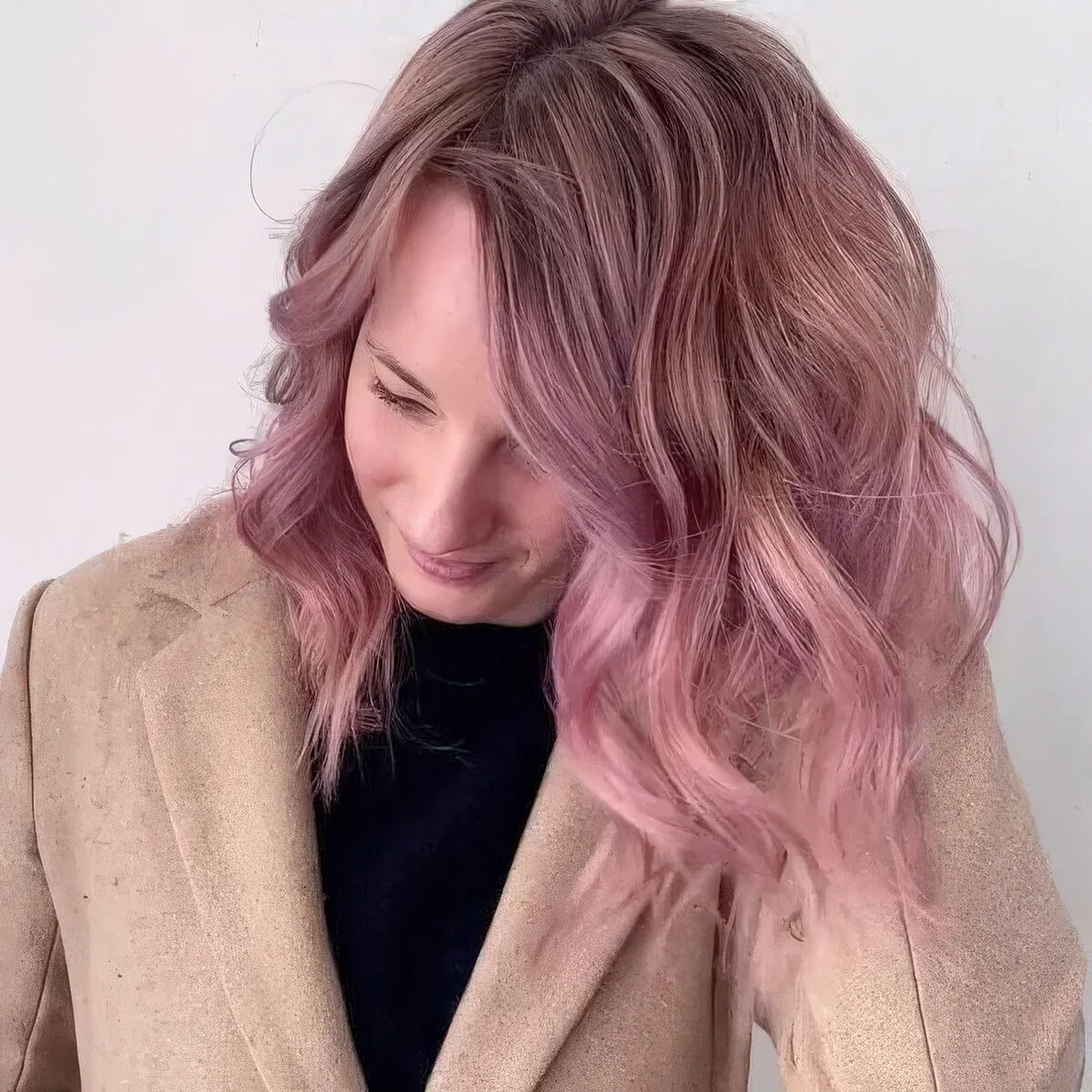 Medium-length pink hair wiht a dark root and waves.