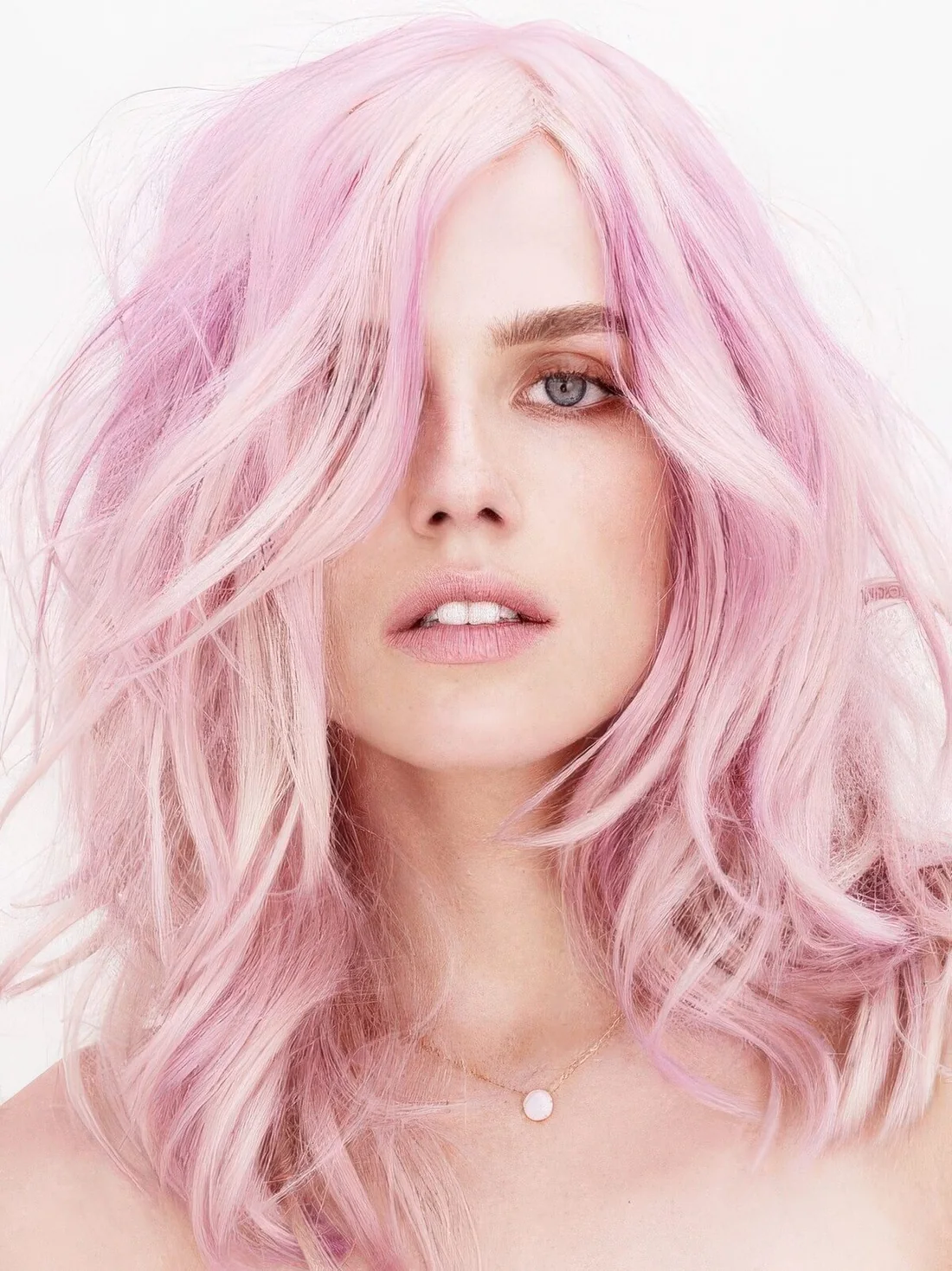 Mid length light pink messy and wavy hair with some layers.