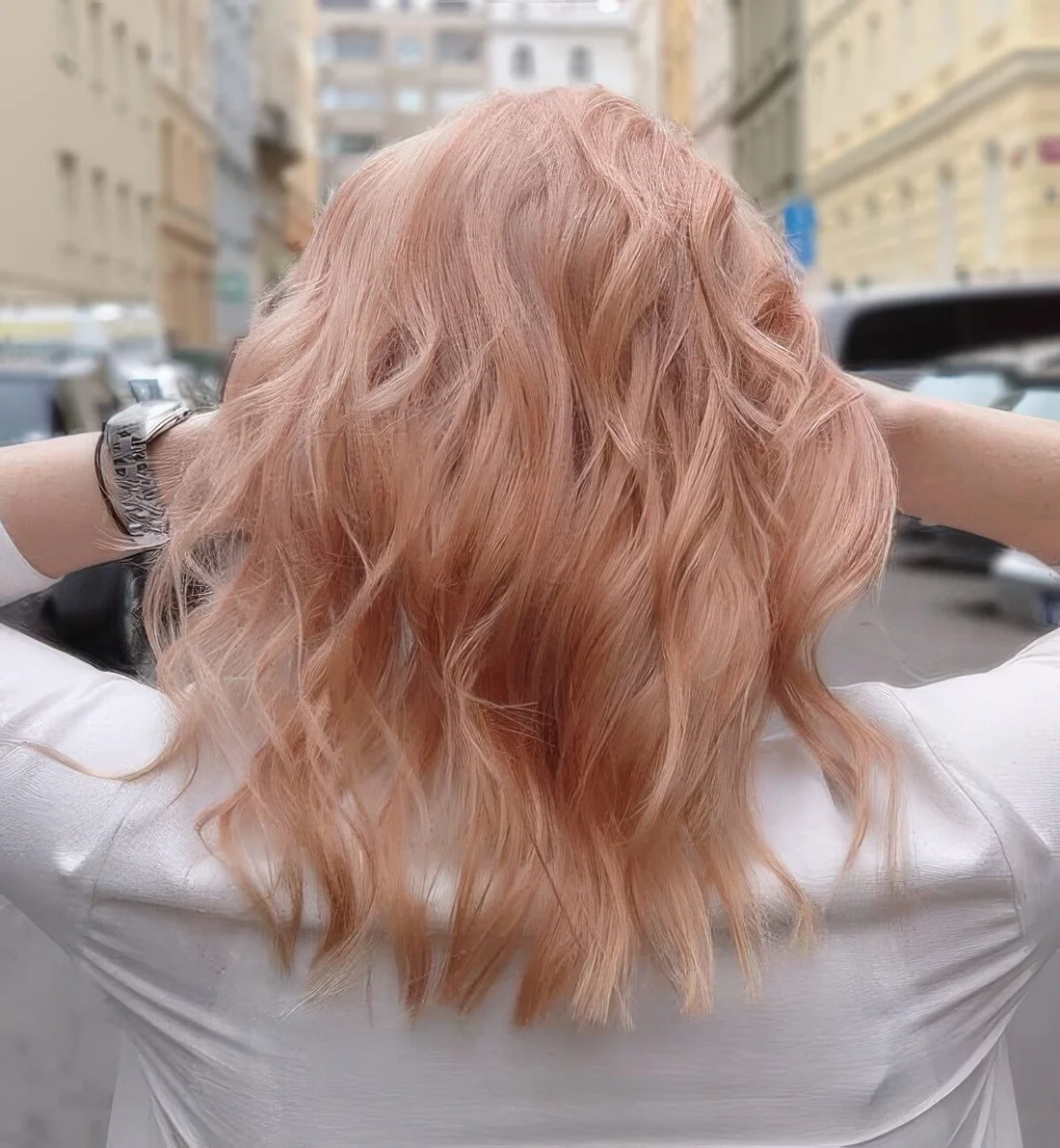 Peachy rose gold medium-length hair with waves.
