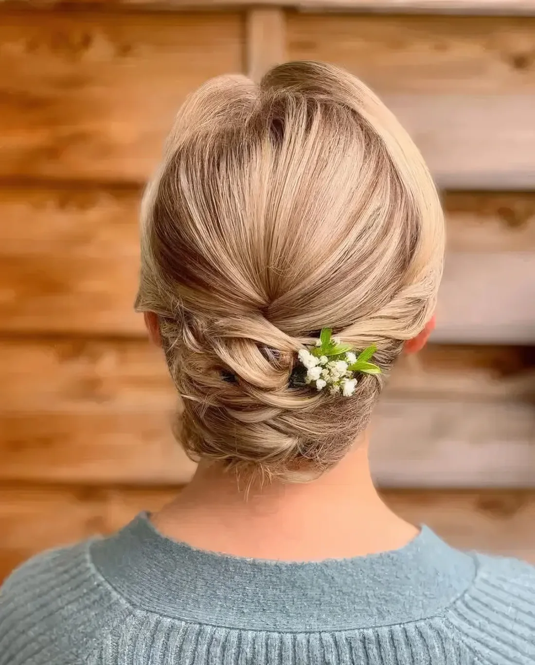 Tight twisted low updo with a sleek top and a bit of fresh blooms.