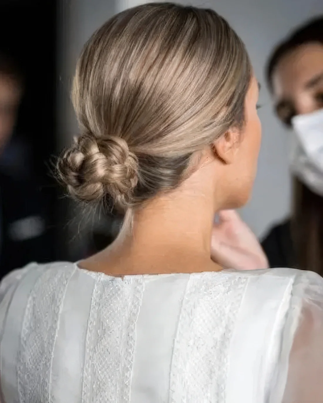 Photo showing braided low bun with a sleek top, with the hairstyle clearly visible.
