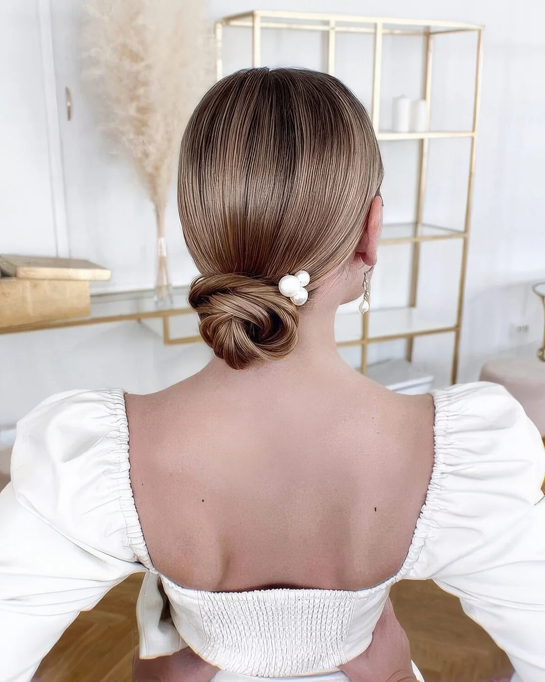 Small sleek wrapped low bun with a sleek top and pearl hair pins.