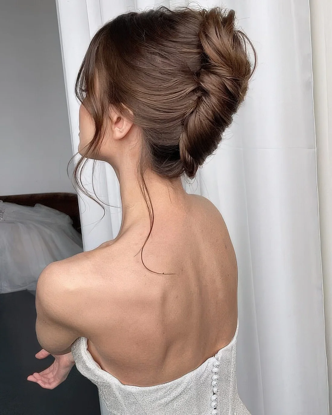 Chingon hairstyle with a messy bump on top and face-framing hair.