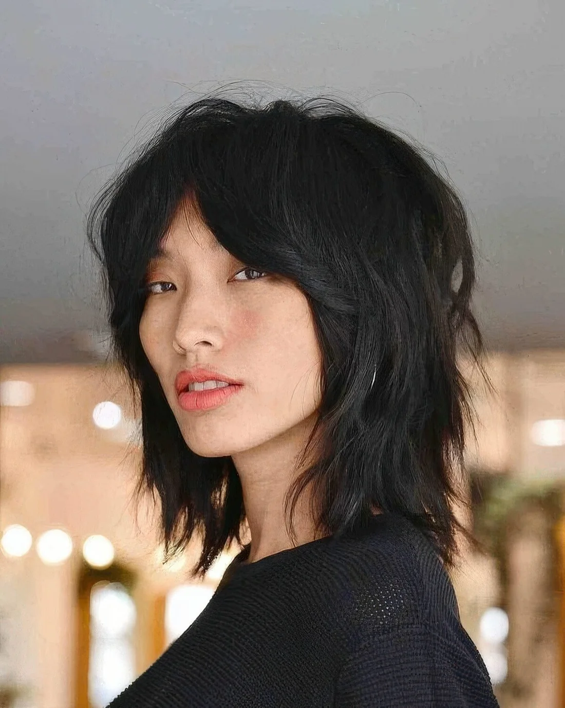 Black wolf cut with bottleneck bangs and layers, with center part.