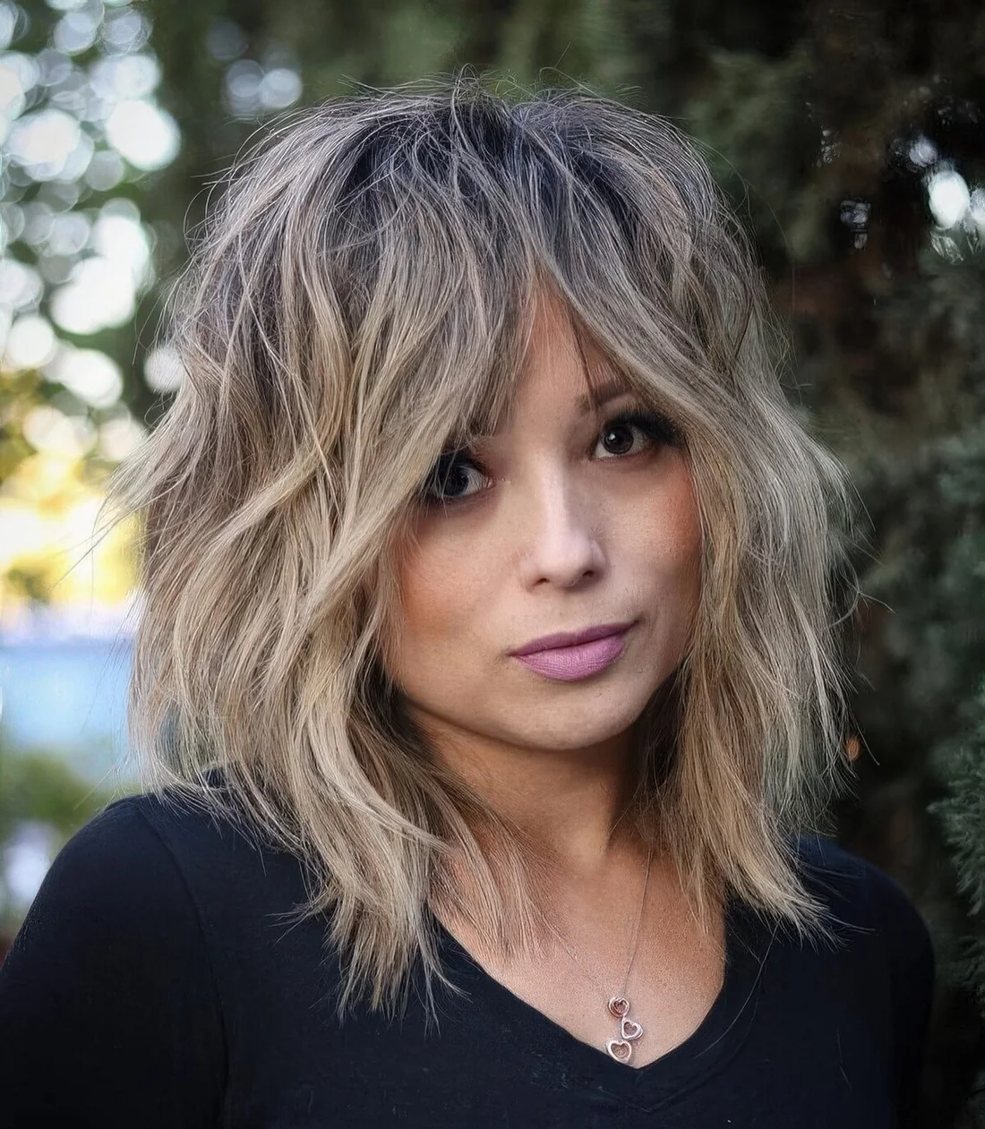 Blonde medium wolf cut with bottleneck bangs, messy texture.