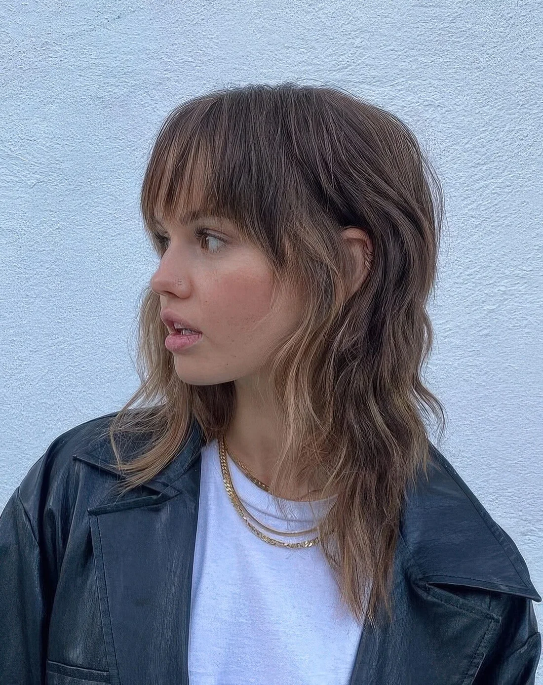 Chic brown wolf cut with caramel highlights, long bangs and layers.